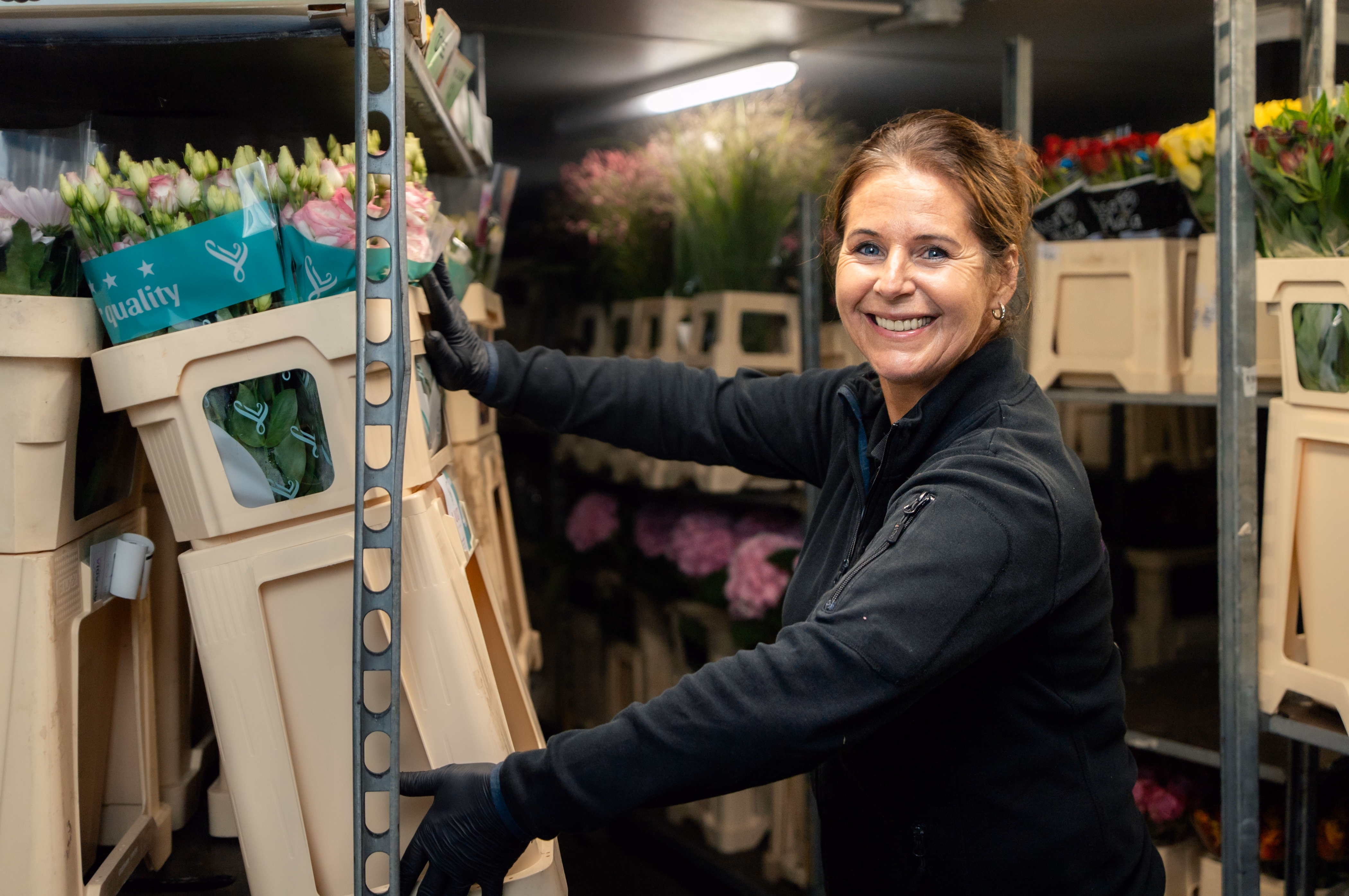 Wilma (eigenaar) met voorraad bloemen in handen